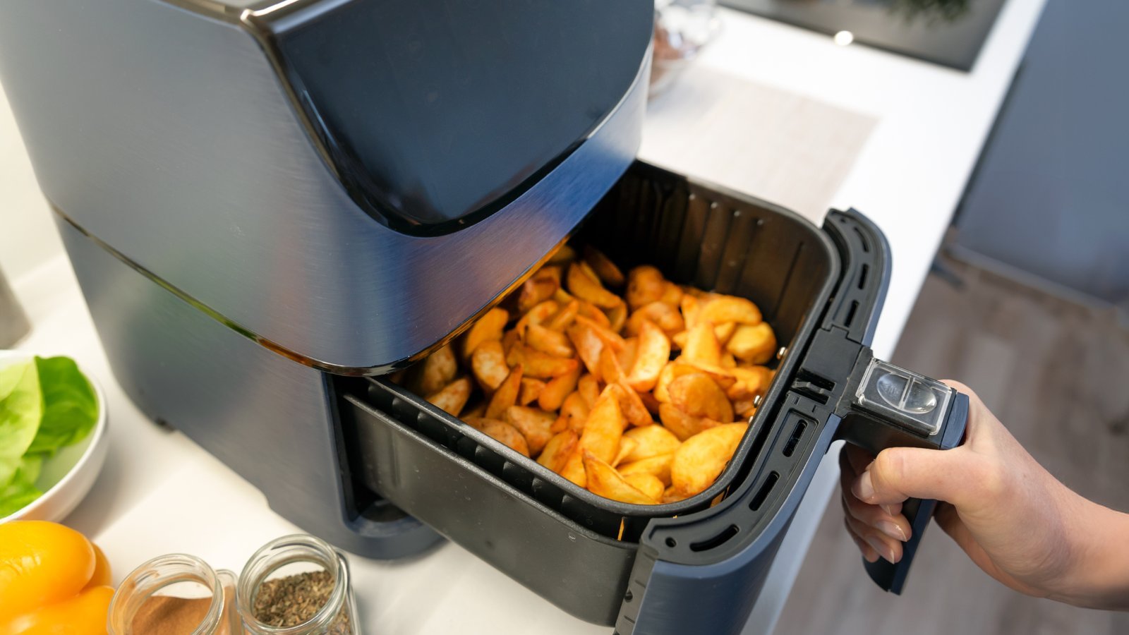 Someone using an air fryer in a bright and organized home kitchen.