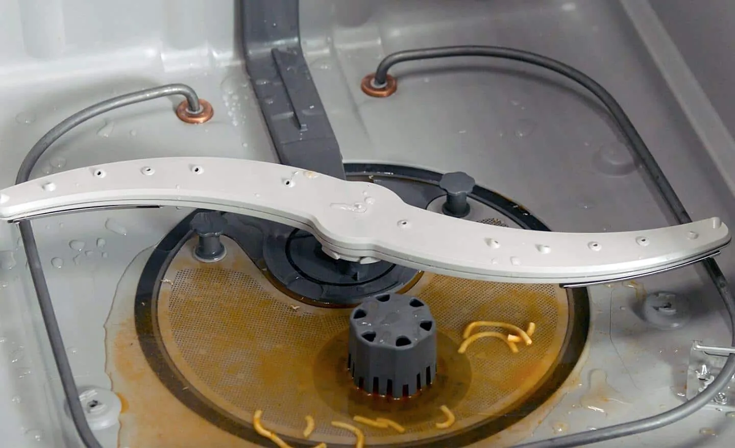 A close-up of the dishwasher drain impeller mechanism inside the basin.