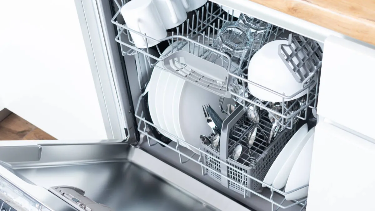 Close up of limescale buildup on the plastic spray arm inside a dishwasher.