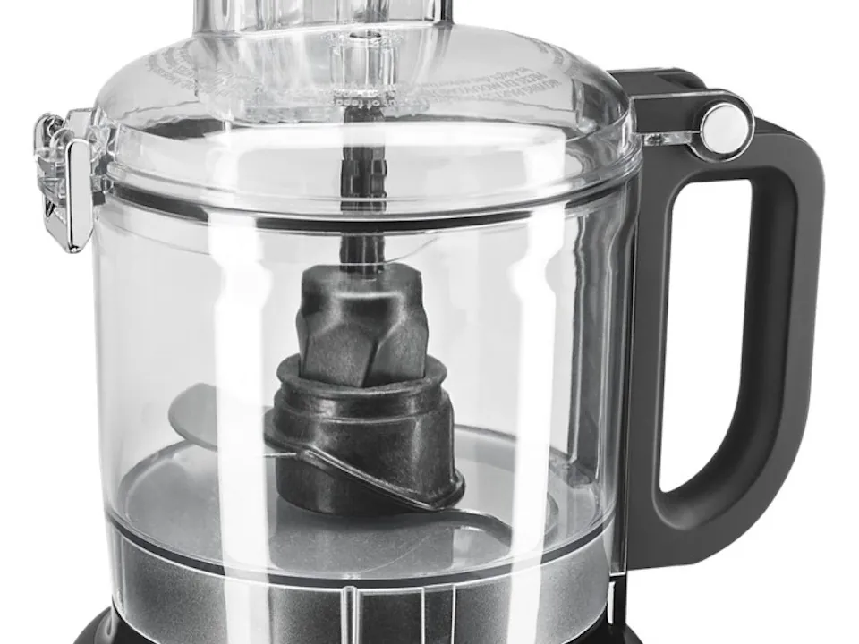 A KitchenAid food processor bowl is placed carefully on the top dishwasher rack.